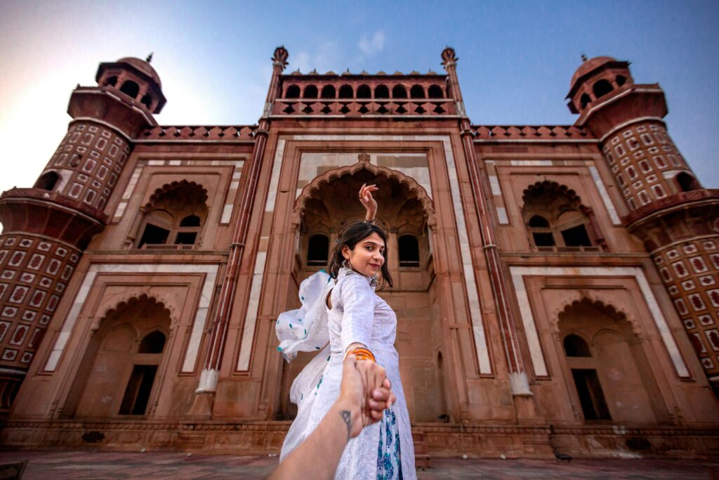 A woman poses at a famous tomb in New Delhi, showcasing architectural beauty.